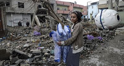 kurdische Frau vor Trümmern ihres Hauses